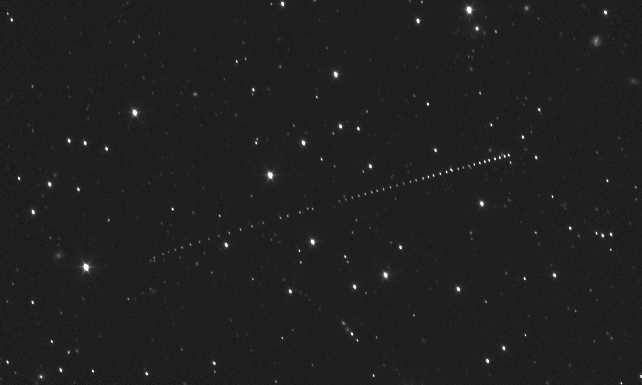 Image of asteroid Donaldjohanson moving across the sky from Feb. 20 to April 5, 2025. The image was created from a series of stacked optical navigation images taken by the L'LORRI instrument on NASA's Lucy spacecraft. The sky is black with bright white dots of varying sizes scattered across. Asteroid Donaldjohanson appears in a slightly diagonal line going through the center of the image.